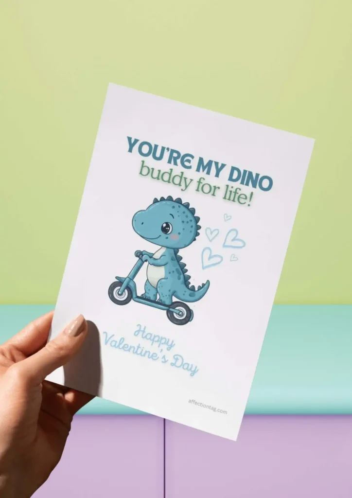 A cute Dinosaur Valentine card showing a blue dinosaur on a scooter surrounded by heart doodles, captioned "You're my DINO buddy for life! Happy Valentine's Day." ©affectiontag.com